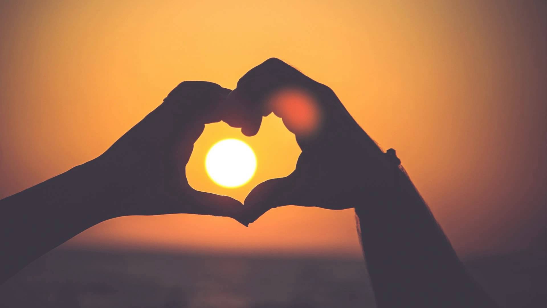 mains en coeurs avec un couché de soleil